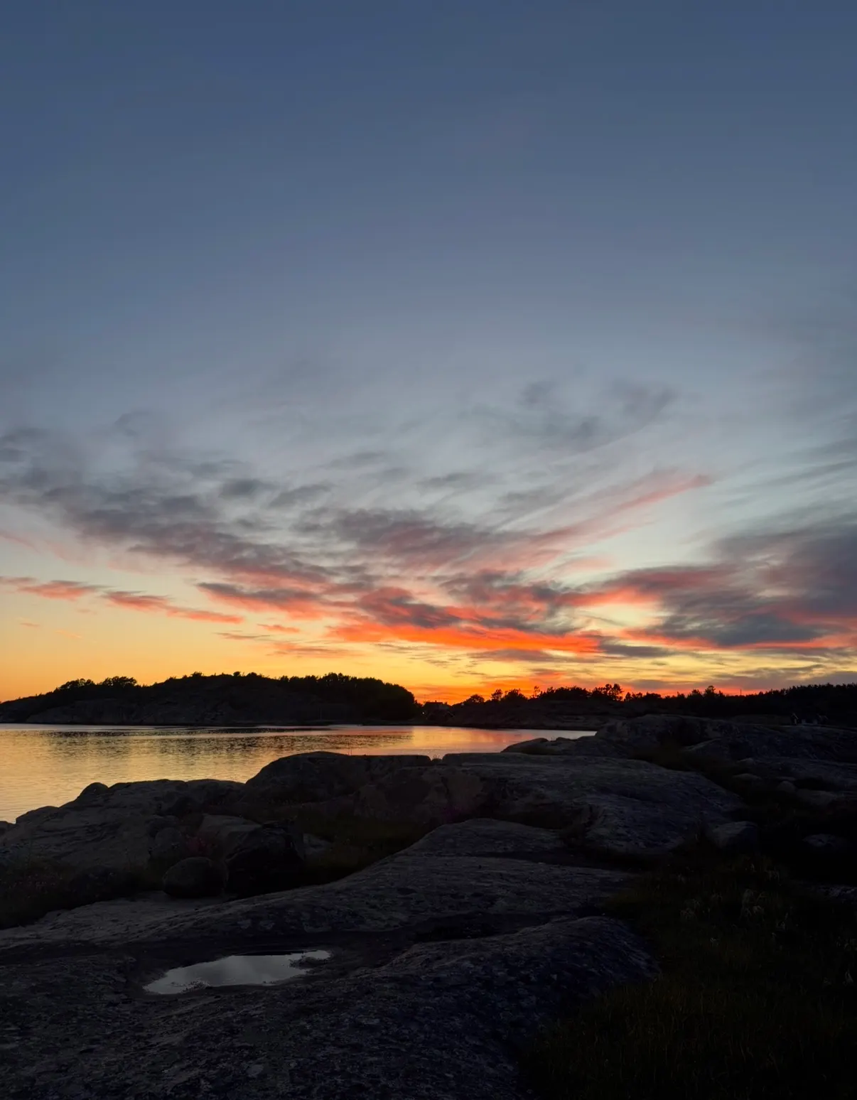 Klippor vid vattnet i lågt kvällsljus.